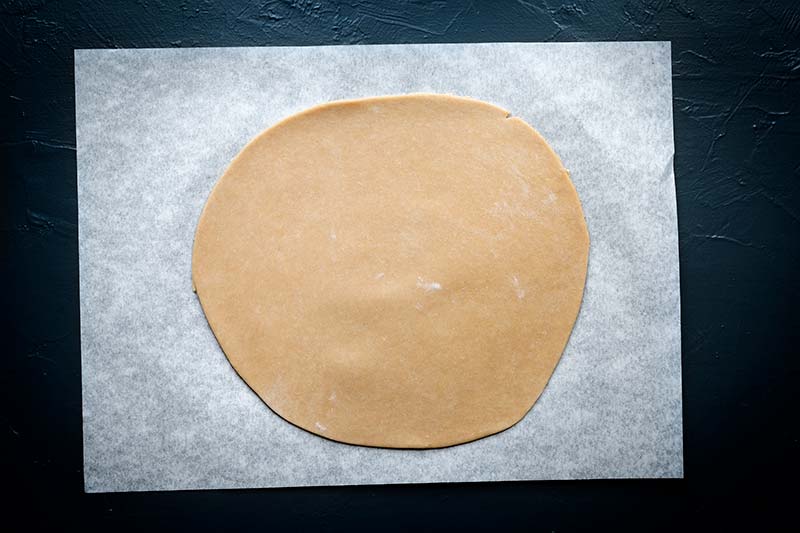 Tart dough rolled out on parchment paper