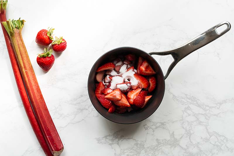 Strawberries and rhubarb in a saucepan with sugar