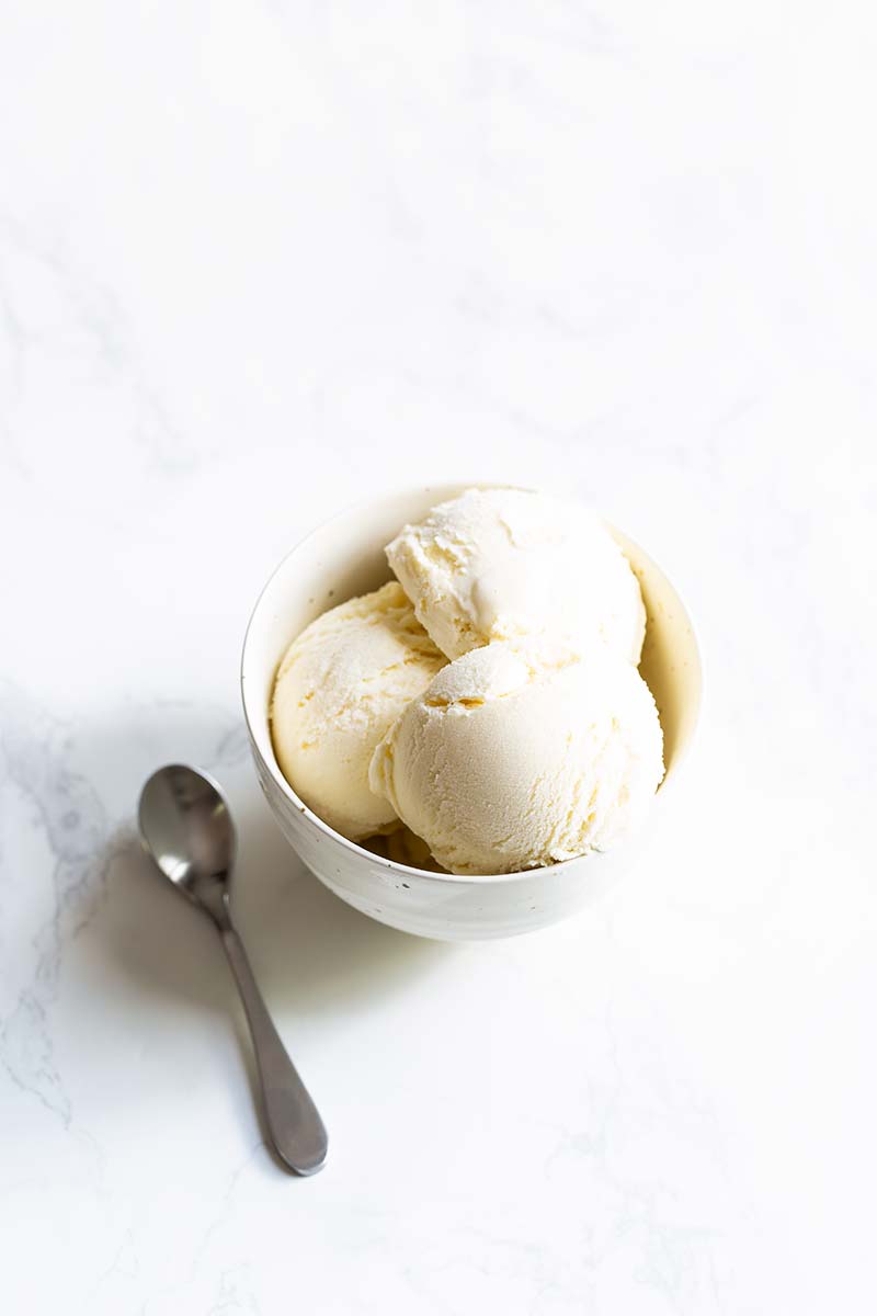 Several scoops of gelato in a bowl next to a spoon